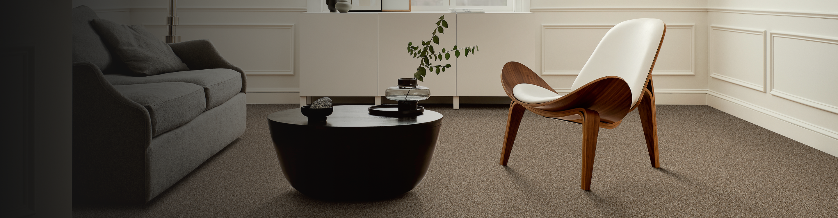 Sitting area with brown carpet and a wooden accent chair